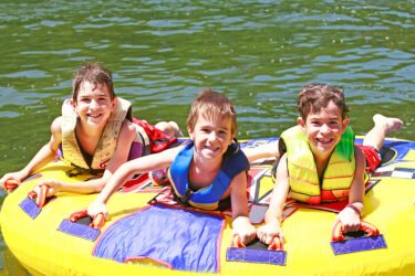 three boys tubing on a lake at sleepaway camp