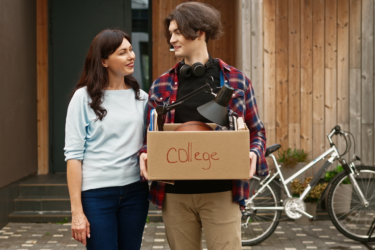 mom talking to son moving out with a box to go to college