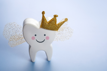 a tooth with a smiley face, crown, and fairy wings