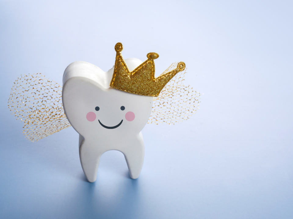 a tooth with a smiley face, crown, and fairy wings