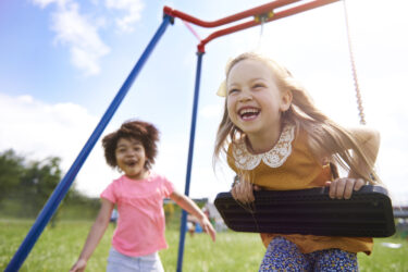 two kids playing on a swing set