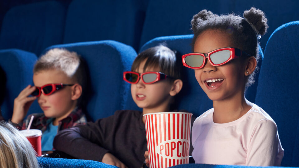 children watching a movie in a movie theatre with poporn and 3d glasses
